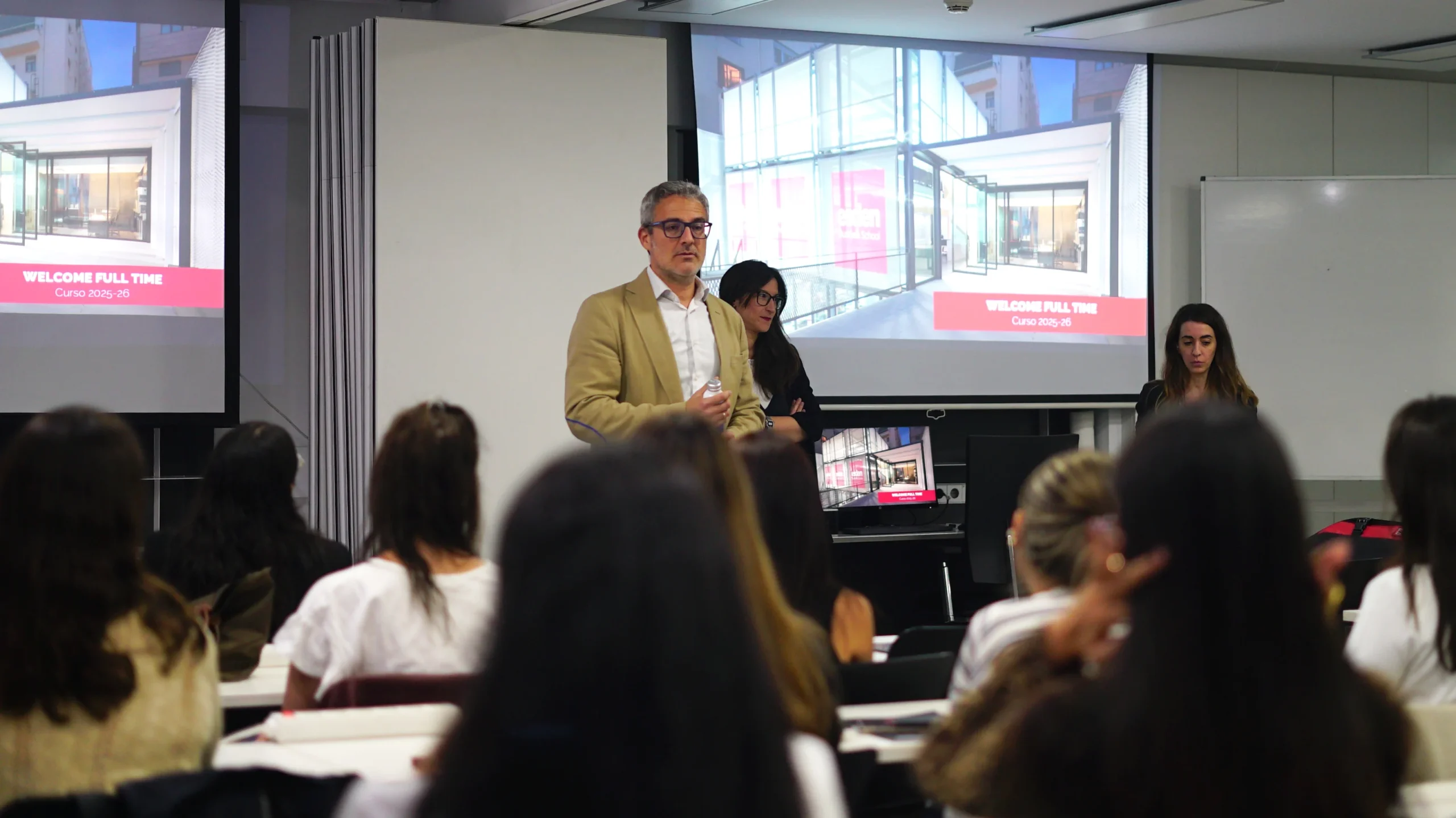 Director de la escuela, dando el discurso en el aula a los alumnos nuevos sentados escuchando