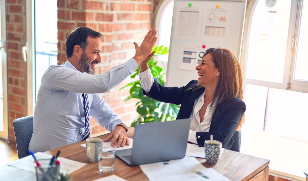 Hombre y mujer chocan las manos en un entorno profesional.